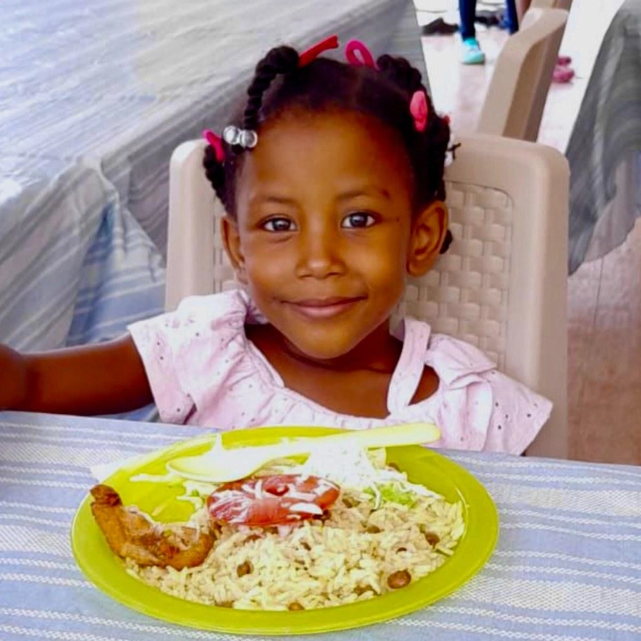 Smiling young girl enjoying a nutritious meal at Bright Stars for the Children in the Dominican Republic.